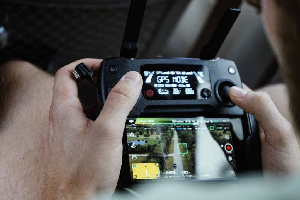 Close-up of hands operating a modern drone controller with GPS mode displayed.