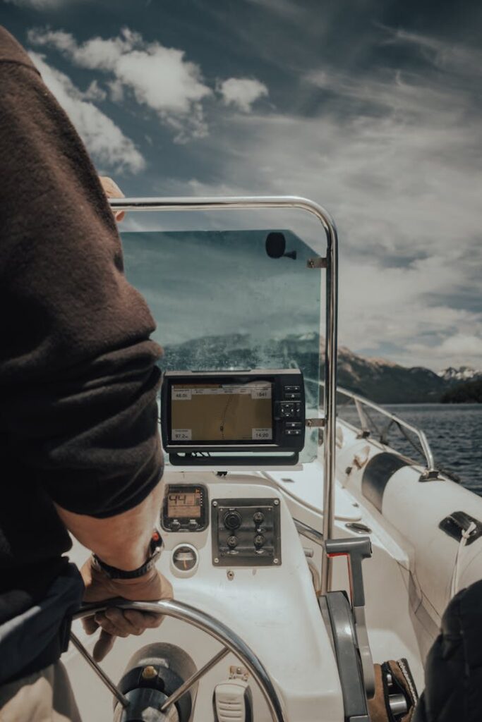 Adult navigating a motorboat with GPS system on a sunny day.